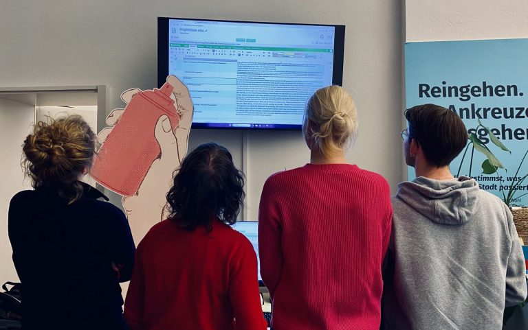 Vier Menschen stehen vor einem Bildschirm.